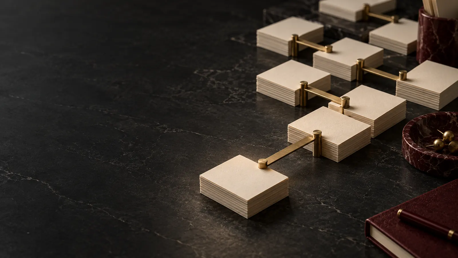 Fiches éditoriales reliées par des ponts en laiton sur une table sombre